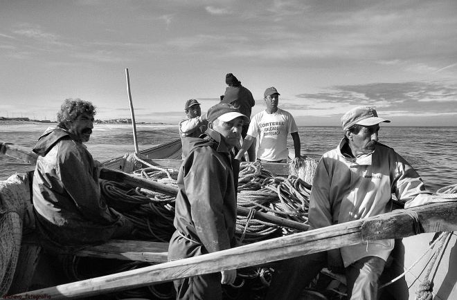 encostado ao castelo da proa vai um homem com máquina fotográfica