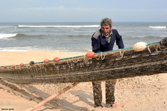 com o bordão, o agostinho ampara e ergue a manga que já se encheu de areia